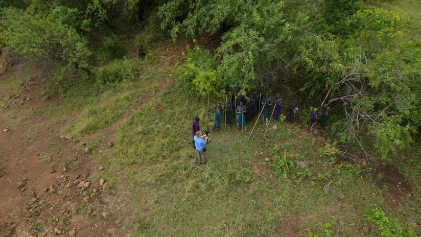 Aerial view of a man photographing tribesman near some trees