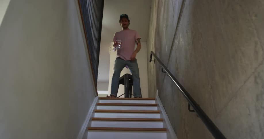 A man with a hat and a glass in his hand sitting on a stool on top of stairs