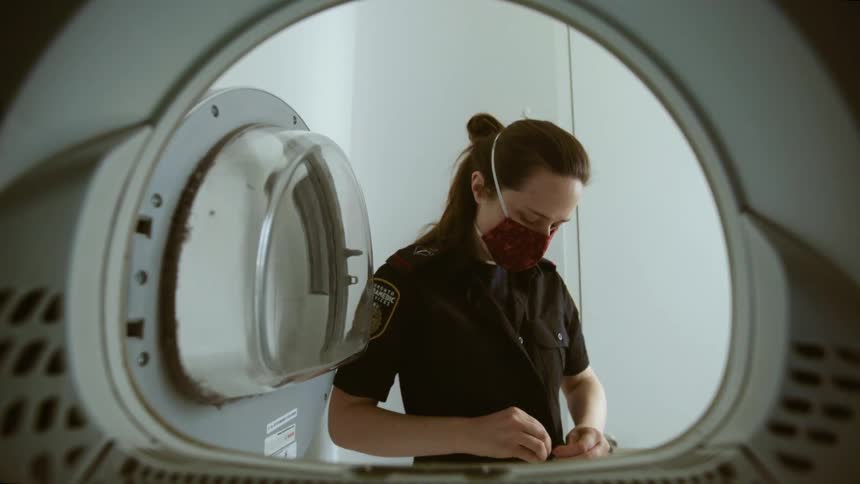 A female first responder takes her overshirt off and throws it into a machine machine
