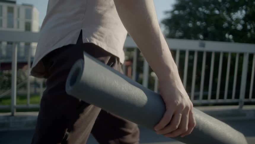 Man walks across bridge carrying paper roll as jogger jogs in opposite direction
