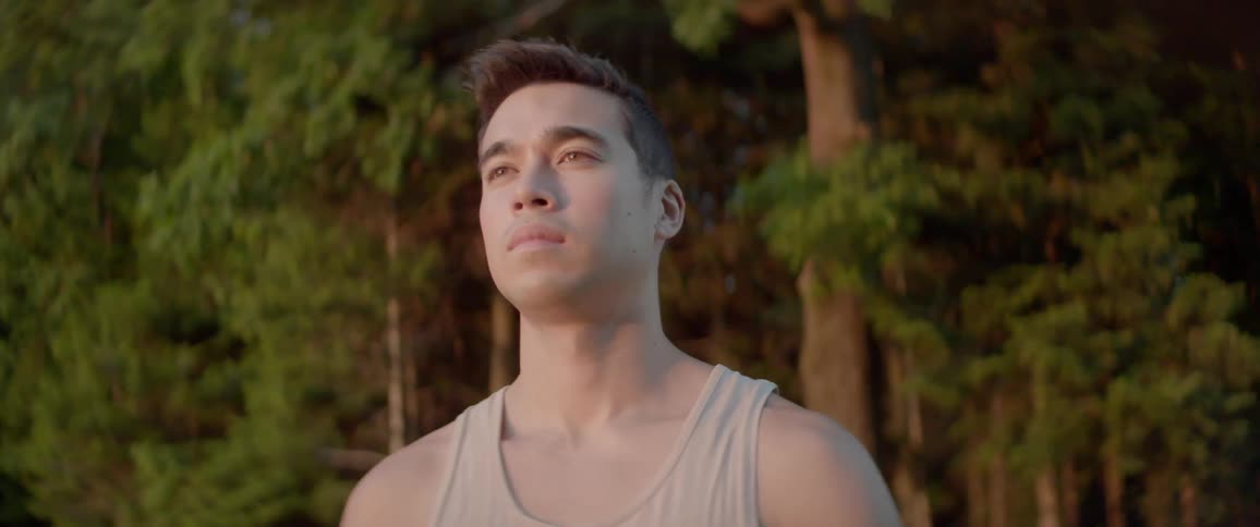 A man is standing outdoors in a forest area