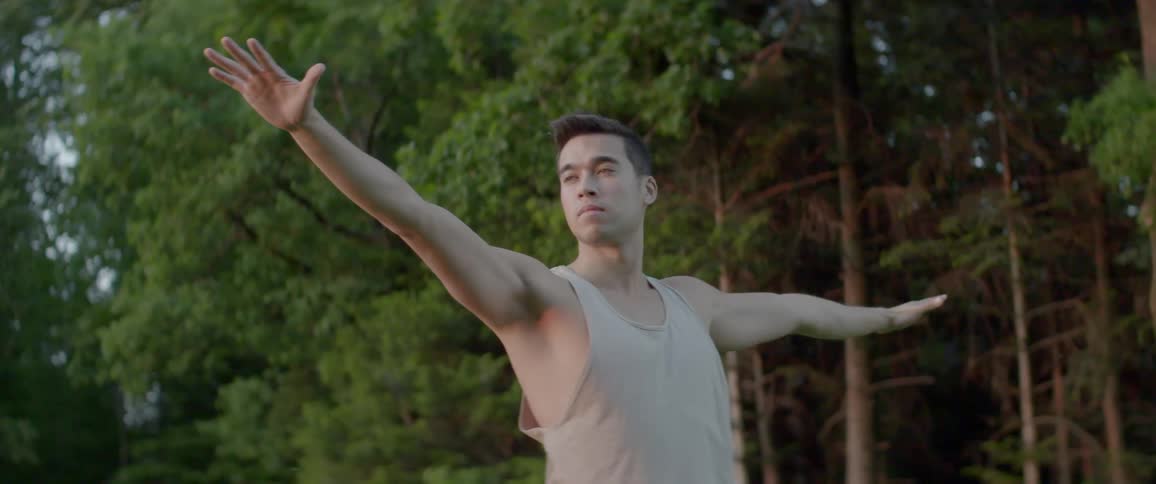 An asian man doing yoga outdoors during the day
