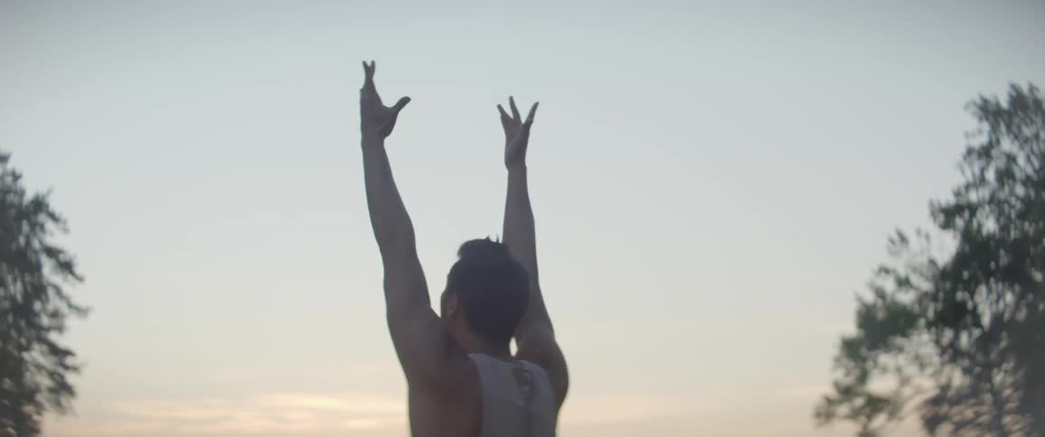 A man is stretching outdoors at dusk