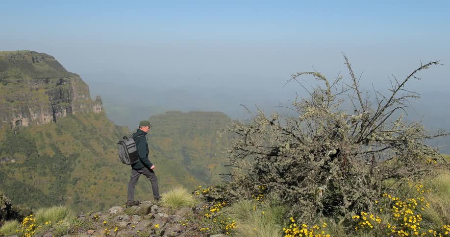 A man is hiking up a mountain on a sunny day