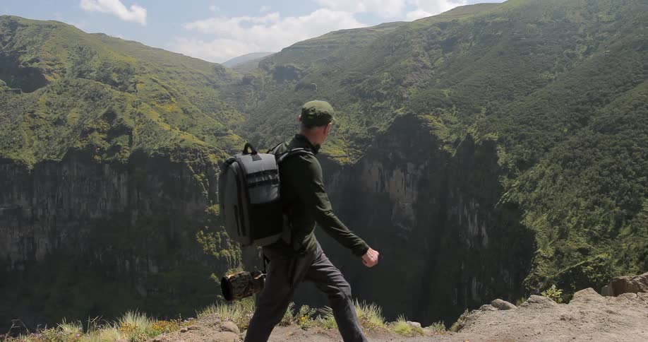 A man is hiking along the edge of a cliff on a cloudy day