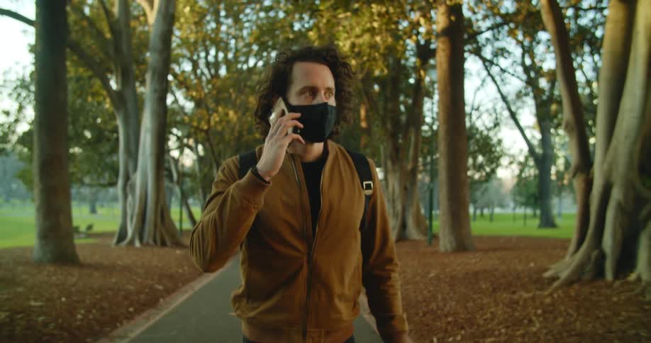 A man is walking outdoors while wearing a mask