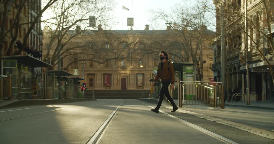 A man jaywalks across the street in a city neighborhood