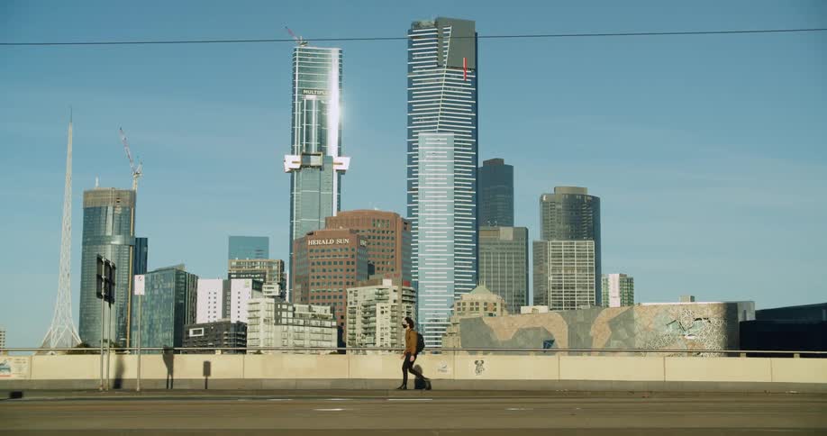 A man walks past the row of tall buildings