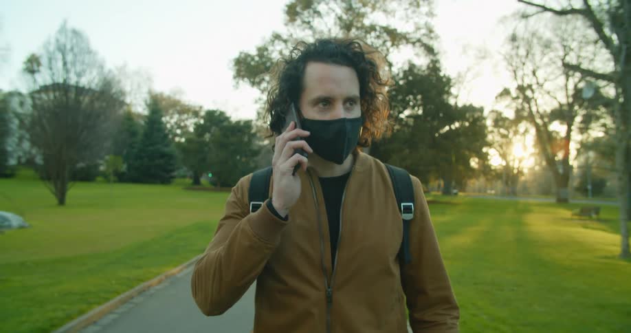 A man is talking on his phone while walking in the park