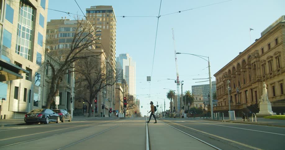 A teenager walking across a quiet city street