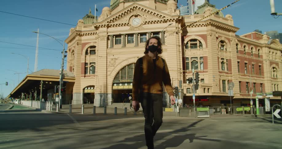 A man crosses the street near a train station in the city