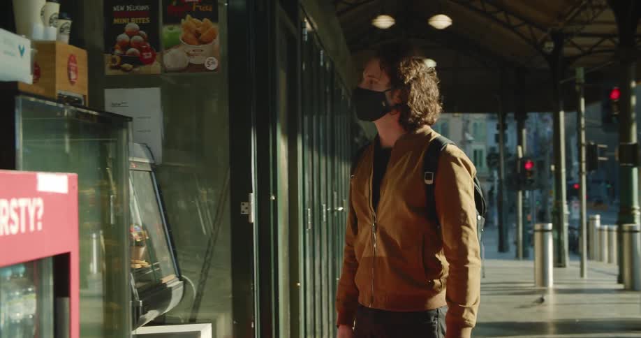 A man is walking in downtown city while wearing a mask