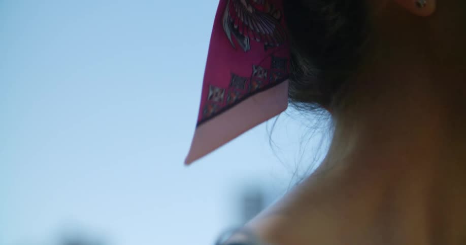 A woman is standing outdoors while wearing a bandanna