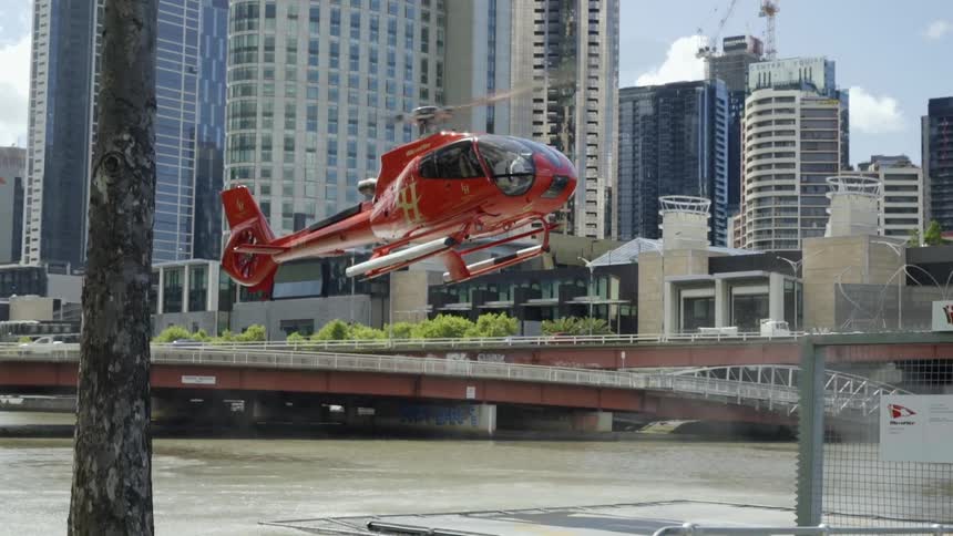 Red helicopter starts landing across river from downtown