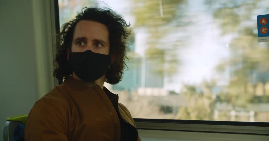 Man wearing face mask rides public transportation through downtown