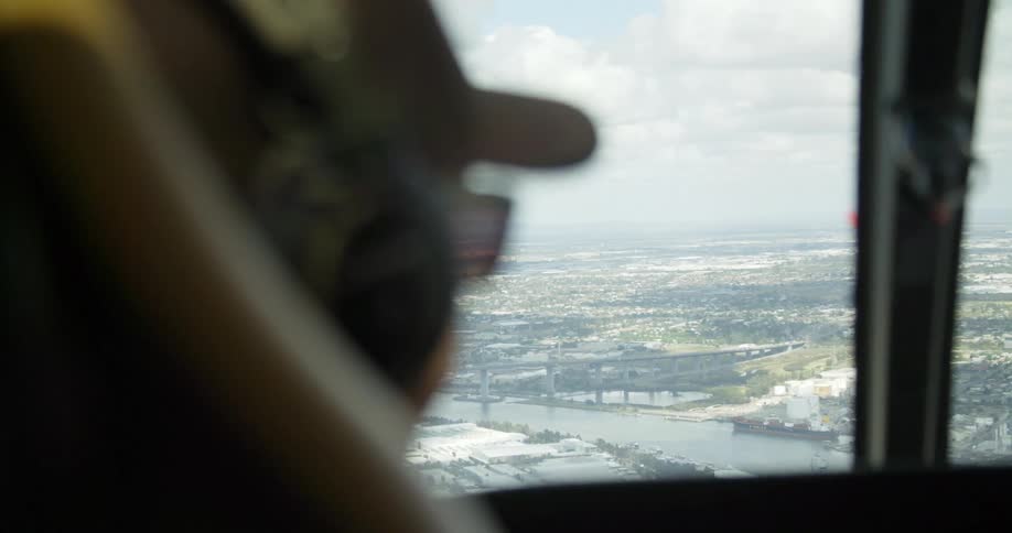 A person inside a helicopter looks at a city and river below