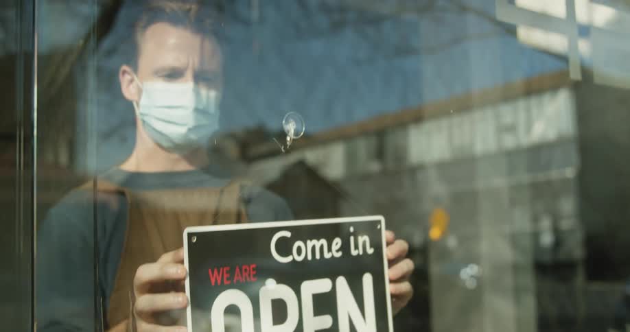 A restaurant owner turns over an open sign to his business in a city