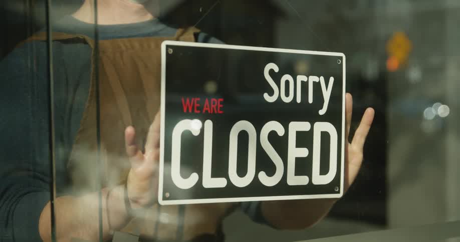 A man flips the business sign from opened to closed