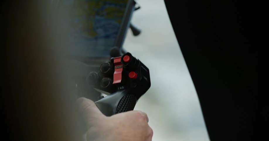 A helicopter pilot holds onto a control stick while flying in the air