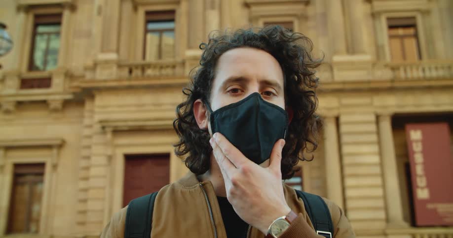 A man is wearing a face mask outdoors in a city