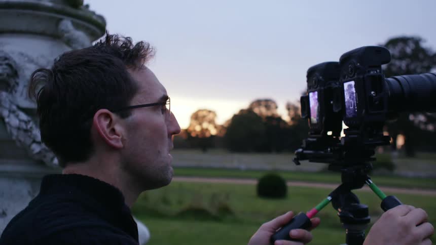 A man watches through his camera lens