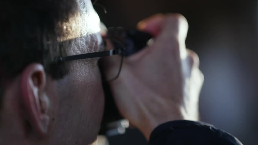 A man looks through the view finder of a digital camera