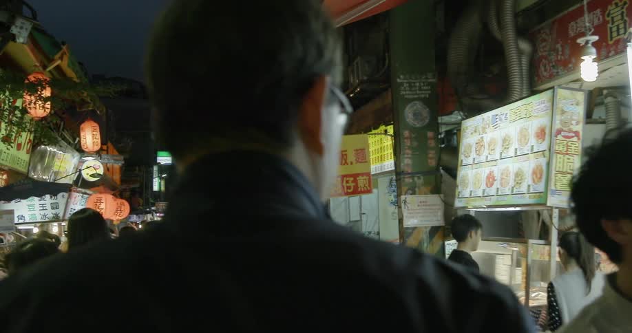 A man walking in a crowded street at night