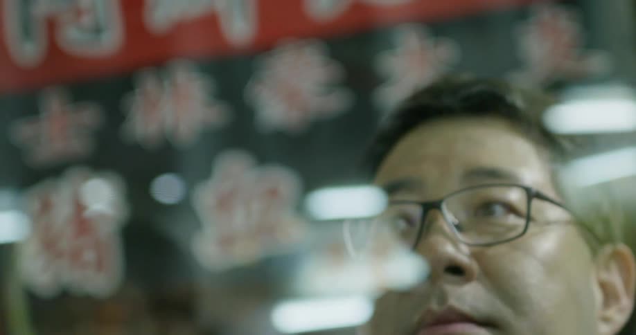 A man stands and looks through a window