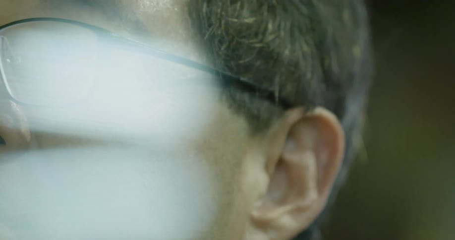 A caucasian man with glasses stares at something in front of him