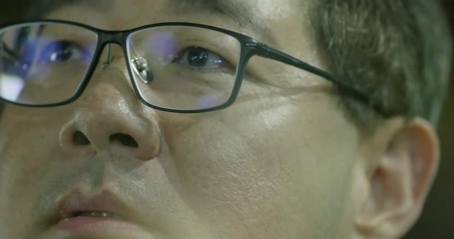 Close up of man with glasses staring at screen