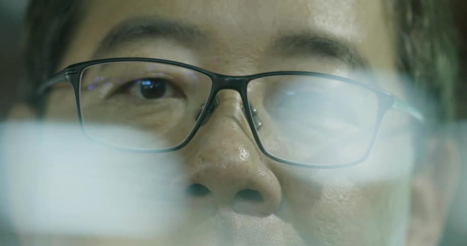 Lights pass in front of a mans face with glasses