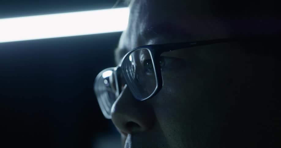 Man with glasses attentively staring at screen