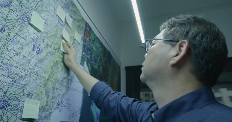 Asian male placing a note on a large map on wall