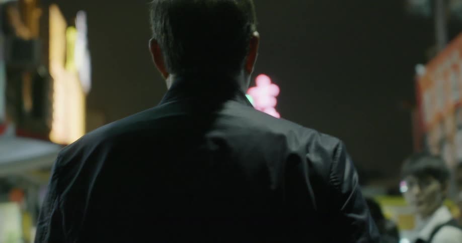 A man walking down a street in a city at night