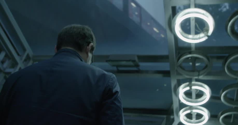 Man walking down a hallway under a train track