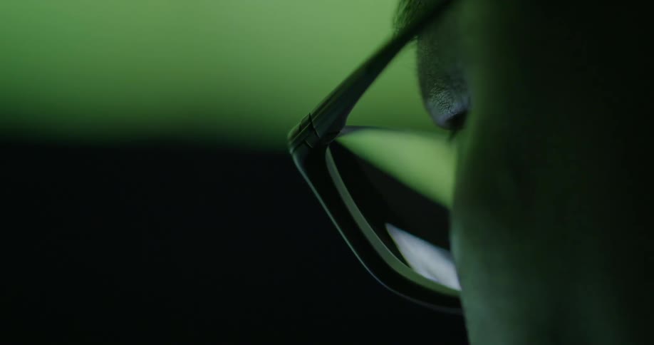 A man looking through glasses on the dark