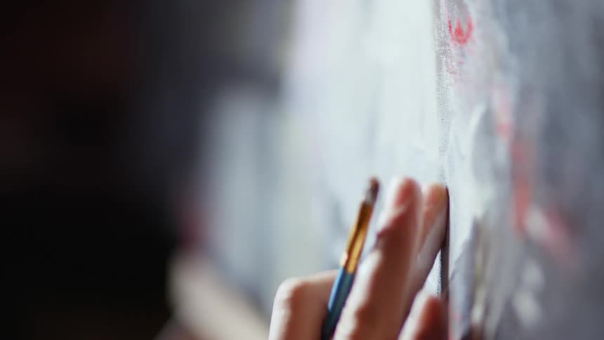 Man painting an oil painting on canvas with a brush