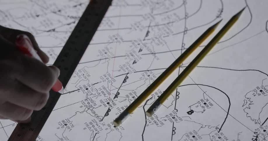 A man uses a ruler to draw a line on a blueprint