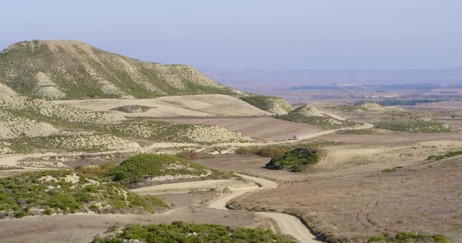 The vehicle drives on the bending dirt trail