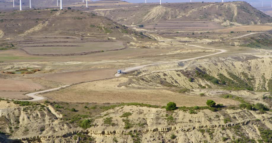 A truck drives down a curvy road through the desert
