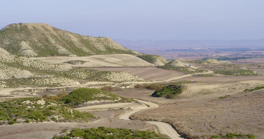 A truck travels on a winding desert road