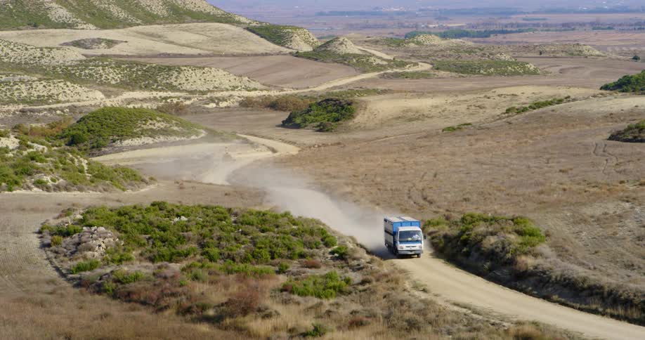 Box truck drives through desert on dirt road