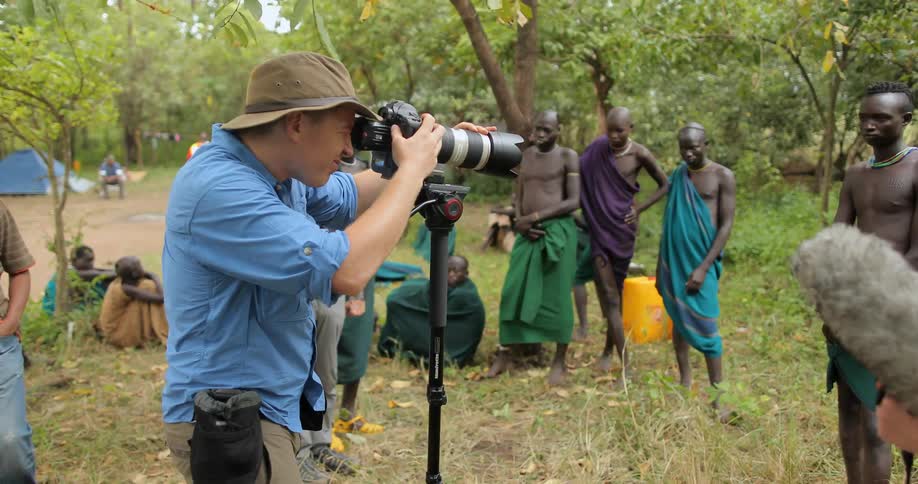 A man is photographing villagers in the wilderness