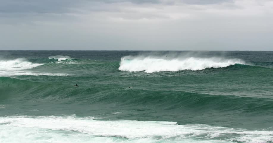 People on surfboards in the ocean with waves with the sky in the background