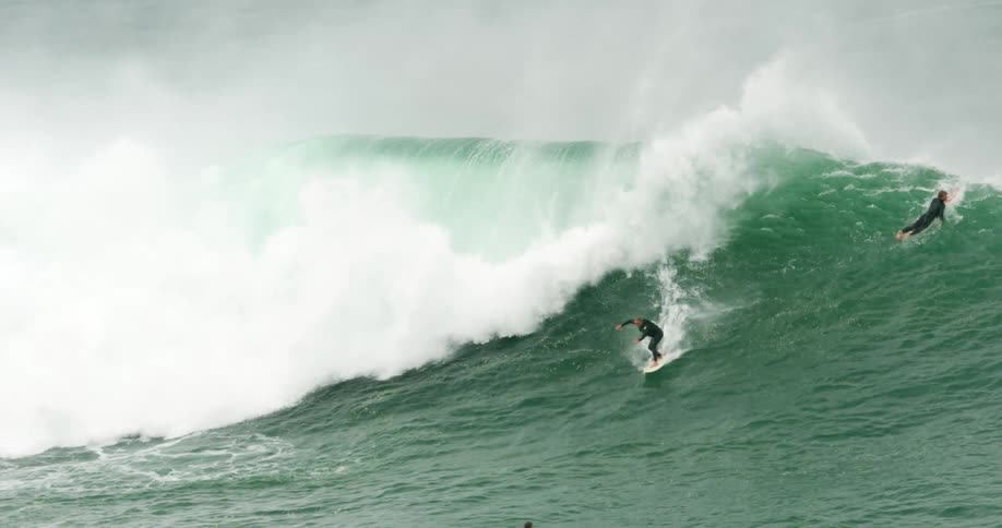 A person is riding a large wave on his surf board