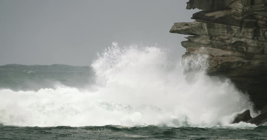 Ocean waves crashing into a rocky cliffs on a cloudy day