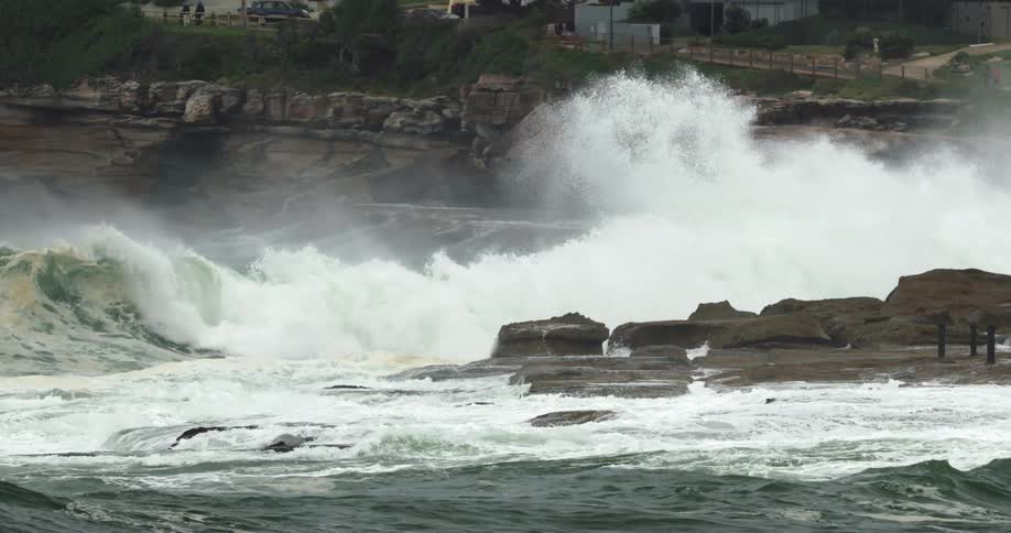 Ocean waves crash onto a rock formation just off the coast of city