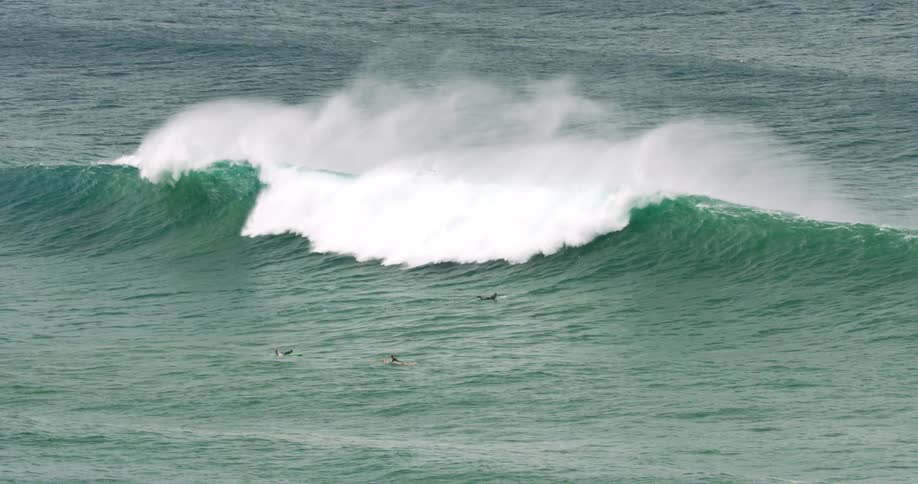 A large ocean wave washes over a group of surfers
