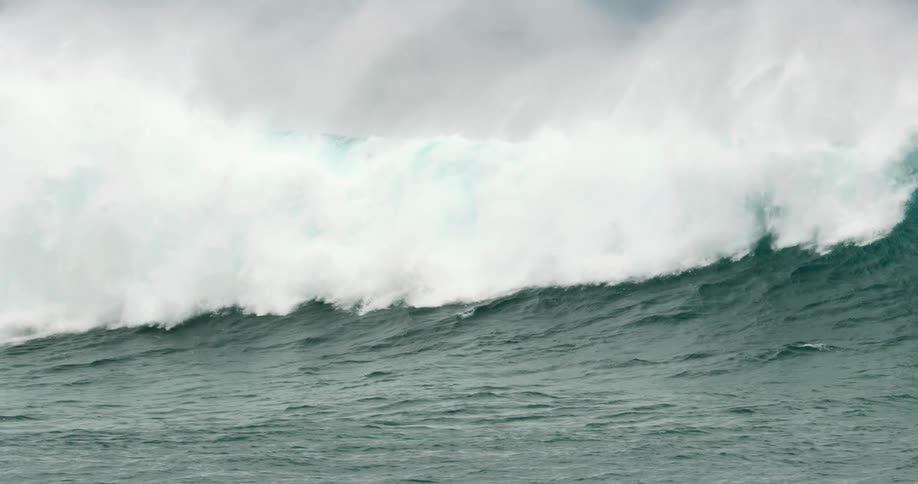 A bluegreen ocean wave crashing down on a trio of surfers sending one surfboard into the air