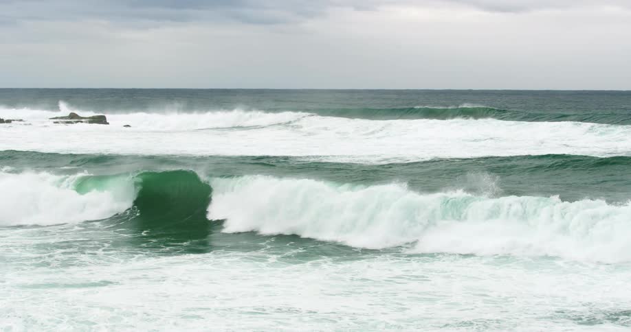 Bluegreen waves washing into the coast on a cloudy day